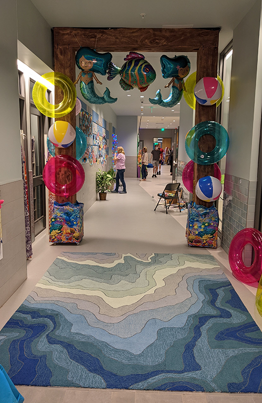A hallway decorated with inflatable mermaids, beach balls, and colorful tubes